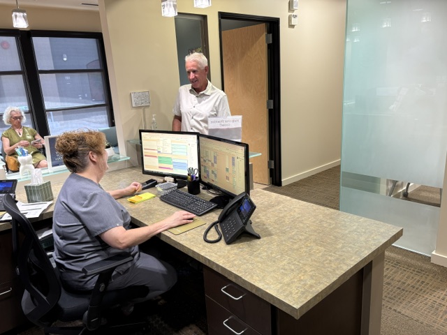 Front desk team member scheduling an appointment while a patient checks in at the practice in Surprise